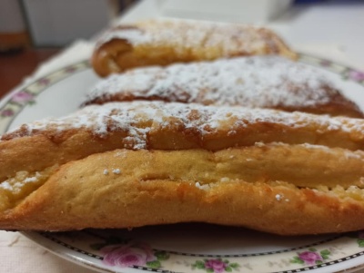 Três pastéis de massa folhada com açúcar em pó num prato branco com flores