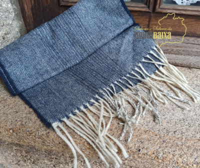 Cachecol azul com padrão espinha de peixe e franjas brancas sobre pedra