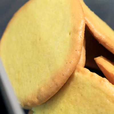 Bolachas redondas amarelas com bordas douradas empilhadas.