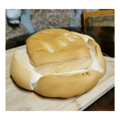 Dois pães brancos sobre tábua de madeira, um redondo e outro quadrado com ranhuras.