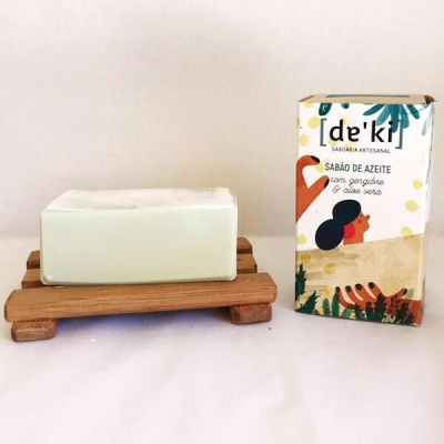 Sabonete branco em base de madeira e embalagem com ilustração colorida