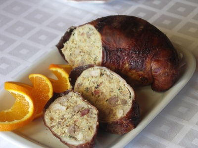 Morcela recheada cortada com gomos de laranja em prato branco sobre toalha branca