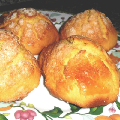 Quatro broas amarelas com cobertura açucarada em prato floral