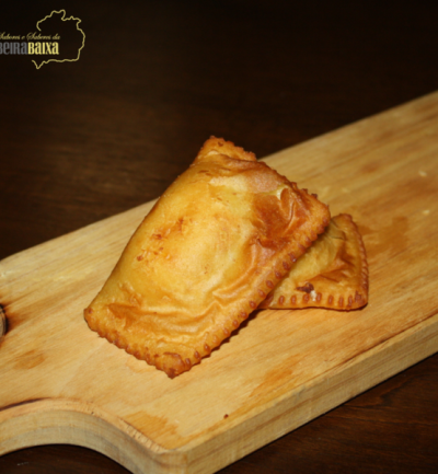 Dois pastéis fritos dourados sobre tabuleiro de madeira clara com fundo escuro e logo Beira Baixa