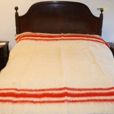 Cama de madeira com cobertor branco e listras vermelhas num quarto