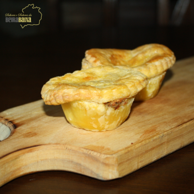 Dois pastéis de massa folhada dourada numa tábua de madeira