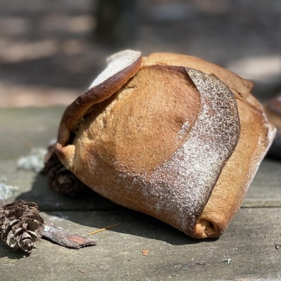 Pão artesanal rústico com farinha polvilhada sobre mesa de madeira