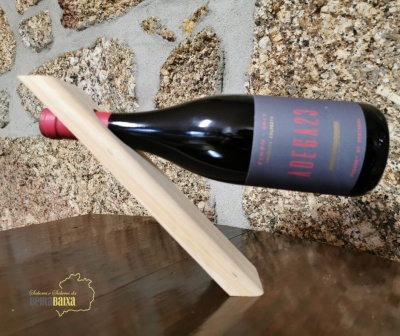 Garrafa de vinho tinto em suporte de madeira sobre pedra e madeira polida