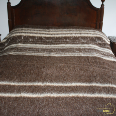 Cobertor castanho com riscas brancas numa cama de madeira