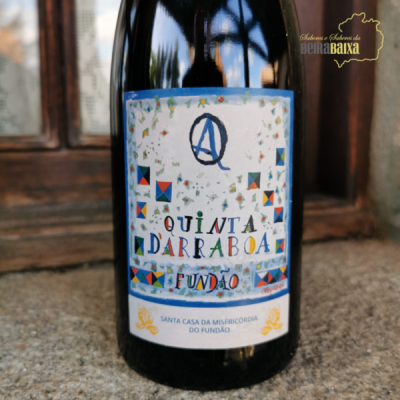 Garrafa de vinho com rótulo colorido e texto em frente a janela de madeira