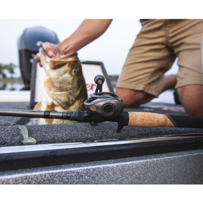Cana de pesca com molinete preto e cabo em cortiça num barco com homem a segurar um peixe grande