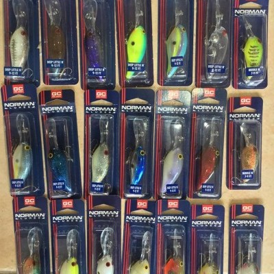 Várias iscas de pesca NORMAN em embalagens individuais com diferentes cores e padrões.