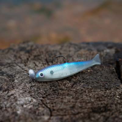 Isca artificial de pesca azul e cinza sobre madeira rústica