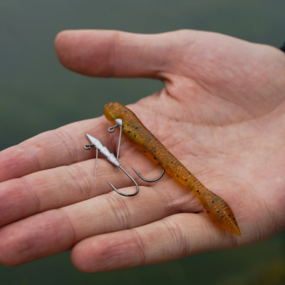 Iscos de pesca em mão sobre fundo desfocado de água