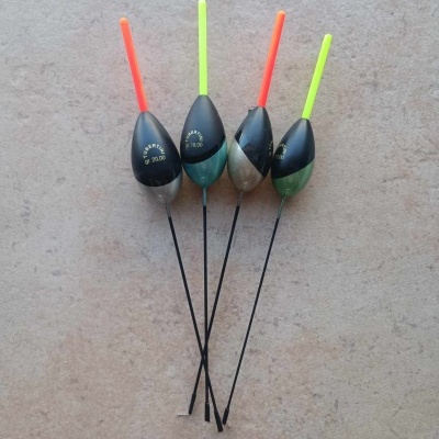 Quatro bóias de pesca com extremidades coloridas e texto dourado sobre azulejo bege