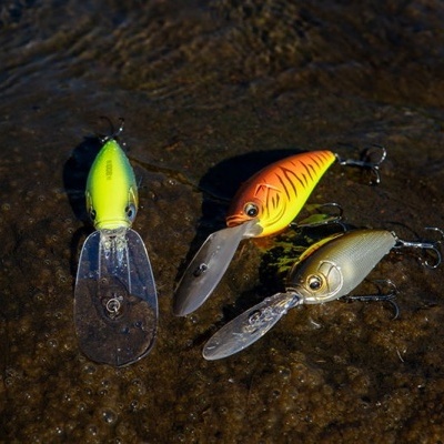 Três iscos de pesca coloridos com anzóis sobre superfície molhada