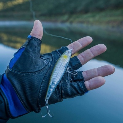 Mão com luva segurando isco de pesca junto a água