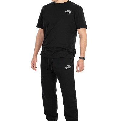 Homem com t-shirt e calças pretas com logotipo branco, boné preto e sapatilhas brancas