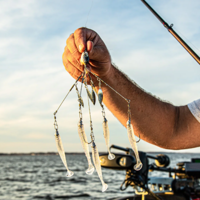 Mão a segurar iscas de pesca artificiais ao entardecer junto ao mar