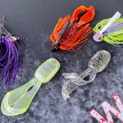 Cinco iscas artificiais coloridas para pesca sobre uma superfície escura.