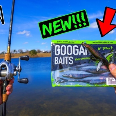 Iscos de pesca GOOGAN BAITS em embalagem transparente com cana de pesca junto a um lago