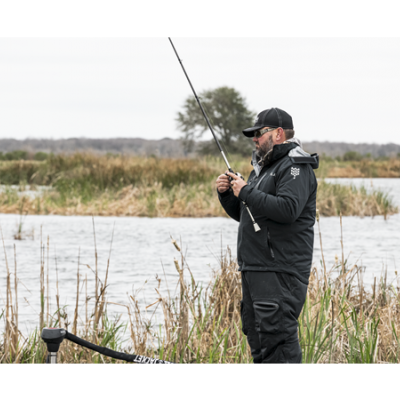 Homem a pescar num lago, vestindo roupa preta, com vara de pesca na mão