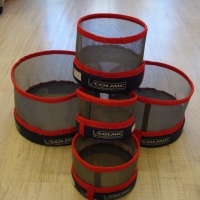 Cestos cilíndricos em malha cinza com bordas vermelhas e etiquetas COLMIC sobre piso de madeira clara