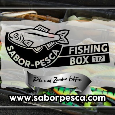 Caixa de pesca preta com iscas artificiais coloridas e adesivo branco com logotipo de peixe e textos promocionais.