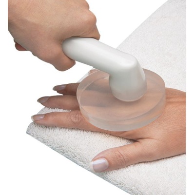 Dispositivo de massagem branco com base redonda translúcida sobre uma mão apoiada em toalha branca.