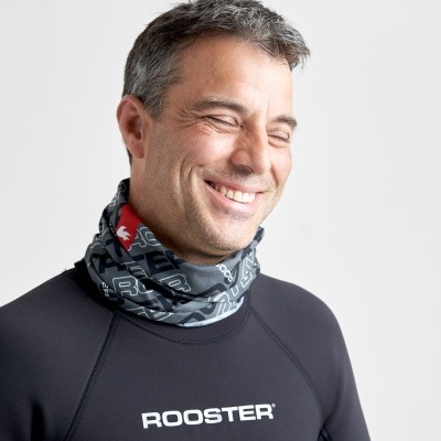 Homem com camiseta técnica preta e cachecol preto com padrão de letras brancas e detalhe vermelho no pescoço