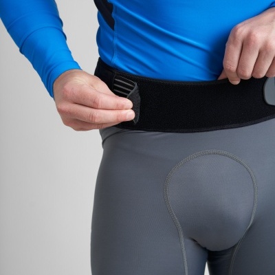 Pessoa a ajustar cinto de velcro preto em calças justas cinzentas e camisa azul