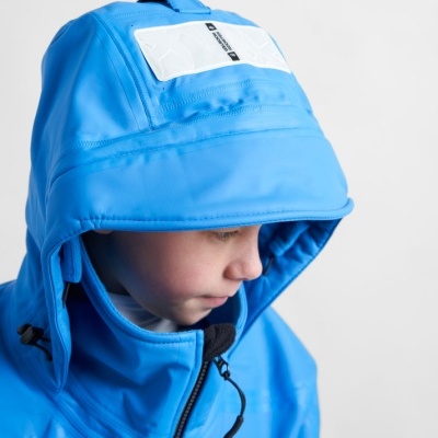 Criança com casaco azul de capuz acolchoado e distintivo branco com texto