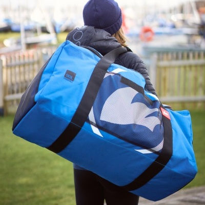 Sacola desportiva azul com padrão branco e azul sendo transportada por pessoa com gorro azul