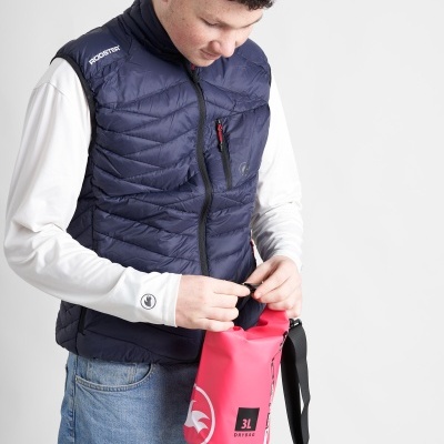 Homem com colete azul escuro e camisa branca a manusear saco impermeável rosa