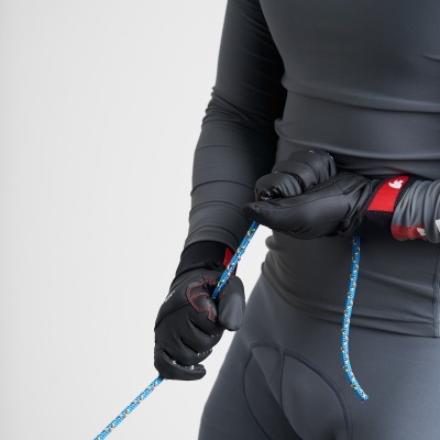 Pessoa com roupa desportiva cinzenta, luvas pretas e corda azul colorida.