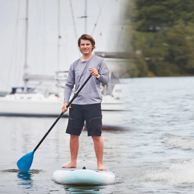 Pessoa a remar em paddleboard branca com azul claro em água calma