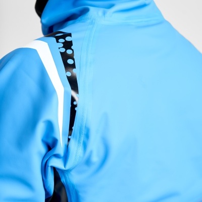 Detalhe da parte superior de uma jaqueta azul com gola preta e detalhes em padrão preto e branco no ombro