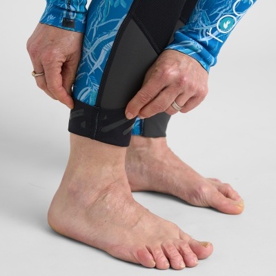 Detalhe de pernas com roupa desportiva azul com padrão de folhas e fecho na perna.