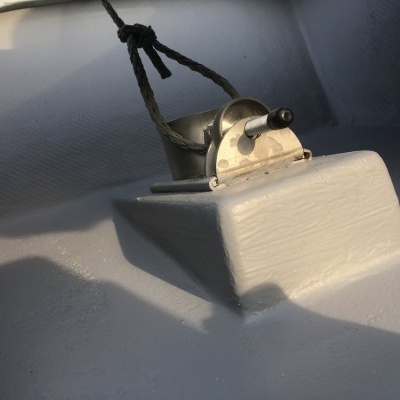 Equipamento metálico prateado fixado em superfície branca com cordão preto