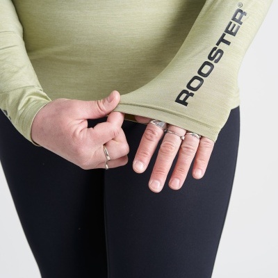 Manga comprida verde oliva com texto ROOSTER® no braço e calças pretas.