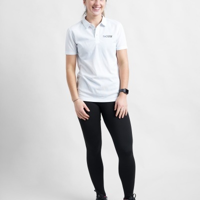 Mulher vestindo polo branca e leggings pretas com sapatilhas pretas em fundo branco