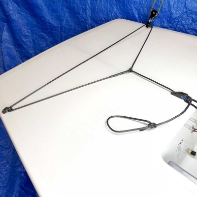 Corda preta trançada com argolas sobre superfície branca e fundo azul