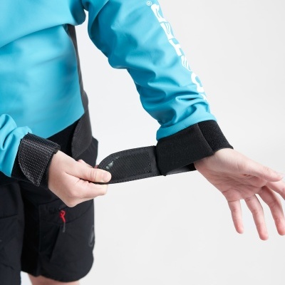 Pessoa ajustando pulseira preta com casaco azul claro e calções pretos