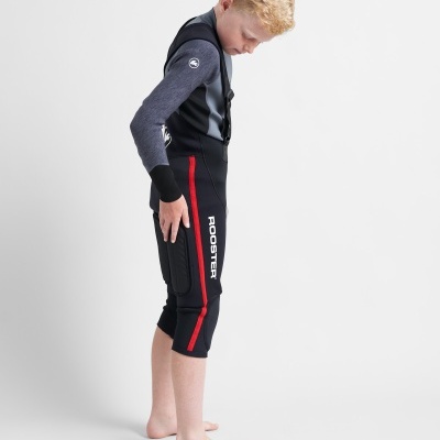 Criança de perfil com fatos de água pretos e cinzentos com detalhes vermelhos.