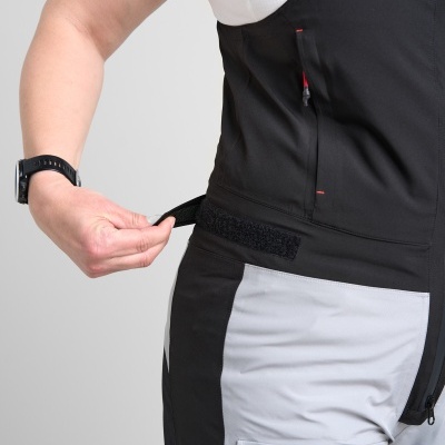 Pessoa a ajustar vestuário técnico preto e cinza com fecho de correr e alfaiataria em velcro na cintura