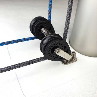 Duas roldanas negras com cabos têxteis azul e cinza numa superfície branca junto a um cilindro metálico cinza.