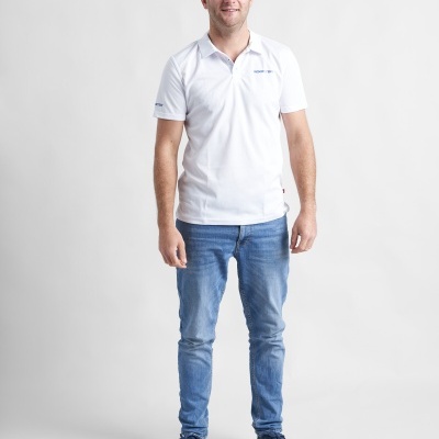 Homem com polo branca e jeans azuis diante de fundo branco
