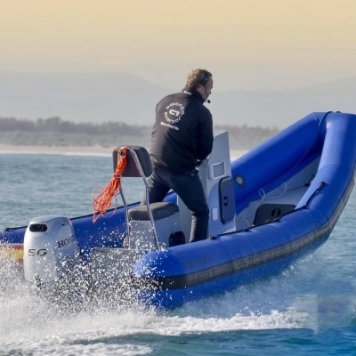 Barco insuflável azul com motor Honda e homem a conduzi-lo na água