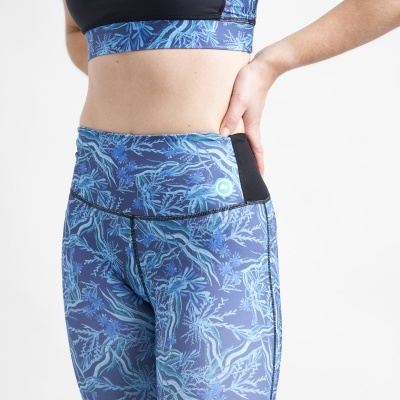 Conjunto desportivo azul com padrão de folhas e ramos, tecido elástico e preto nas laterais das calças.