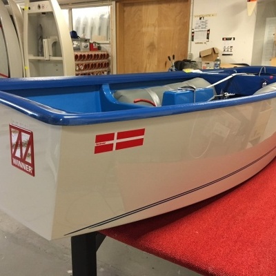 Canoa branca com borda azul, bandeira da Dinamarca e emblema WINNER num espaço interior